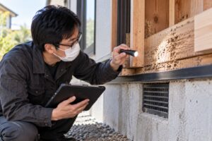 住宅の木部をライトで確認するシロアリ調査スタッフ