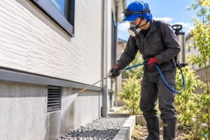 住宅の基礎周辺でシロアリ予防処理を行う作業スタッフ